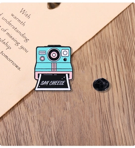 Detail of Polaroid camera enamel pin with Say Cheese text and secure butterfly clasp
