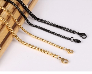 Detailed view of punk style stainless steel box chains in black and gold with lobster clasps