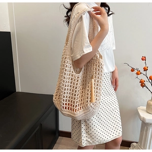 Detailed close-up of beige woven tote bag featuring hollow knit design and fringe tassels