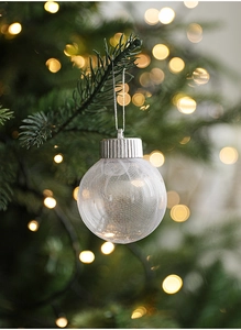 Close-up of a clear Christmas ornament with white web texture on a festive tree branch