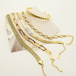 Detail of five gold stainless steel bracelets including paperclip and snake chain styles