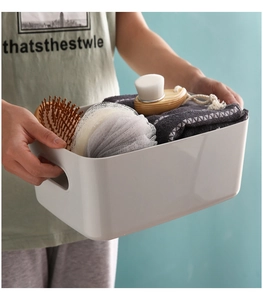 Close-up of a white plastic storage basket with side handles holding toiletries