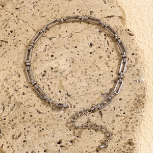 Detail of steel paperclip link chain with cross clasp on a natural stone background