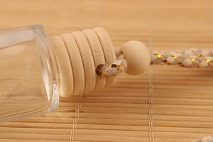 Close-up of 8ml glass car perfume bottle with wooden cap and woven rope on bamboo mat
