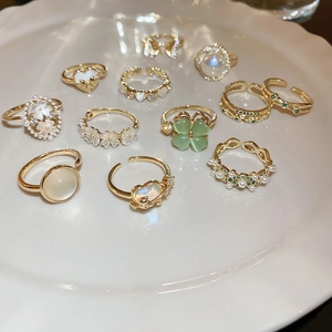 Flat lay of 11 assorted gold-tone rings featuring opal, pearls and heart floral motifs