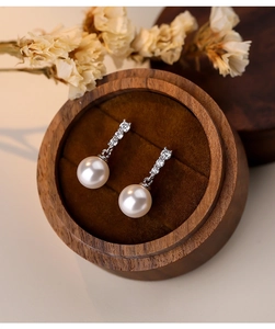 Detail of S925 silver pearl earring with three sparkling cubic zirconia on a jewelry box
