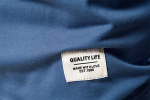 Detail shot of blue cotton fabric texture with a Quality Life woven garment label