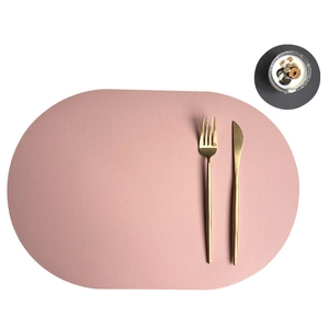 Pink oval PU leather placemat with gold cutlery on a minimalist white tabletop