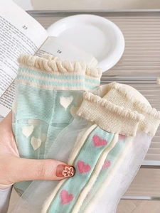 Detailed close-up of light green sheer mesh socks with heart patterns and ruffle edges