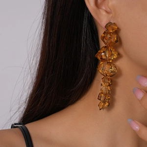 Close-up of amber resin earrings with geometric faceted beads shown on a model