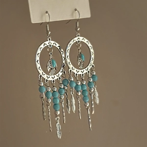 Bohemian silver bird earrings with turquoise beads and feather tassels on a display card