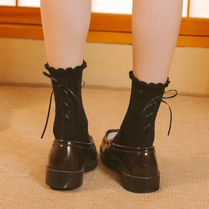 Detail of black knee-high Lolita socks with back lace-up ribbons and ruffled cuffs