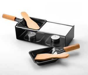 Detail view of double raclette grill set with matte black pans and wooden spatulas