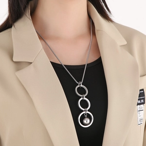 Detail of a silver-tone multi-ring necklace with a bead drop pendant on a model