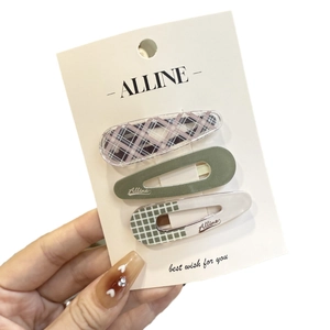 Three-piece hair clip set with pink plaid and matte green patterns on a display card