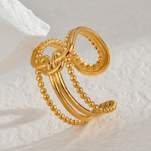 Close-up of a 14K gold plated stainless steel knot ring on a white textured stone