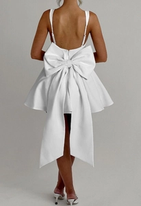 Detailed back view of a white mini puff dress featuring a large decorative bow and open back