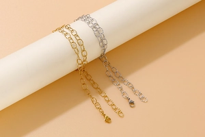 Detail of gold and silver textured link bracelets with lobster clasps on a white display