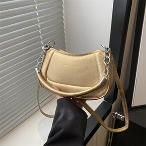 Detailed shot of golden metallic handbag featuring thick rolled handle and silver hardware