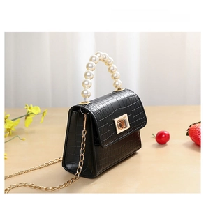 Detail of small black crocodile pattern bag with pearl handle and gold chain strap