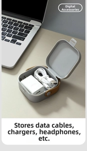 Detail view of grey portable storage box holding a charger and USB cable on a desk
