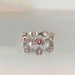 Elegant silver open ring with pink heart-shaped crystals on reflective surface