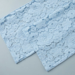 Close-up of light blue floral lace detailing and intricate hollow embroidery fabric