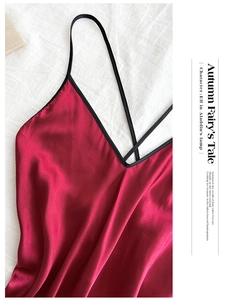 Detail of red satin robe with black silk straps and V-neck on white linen background
