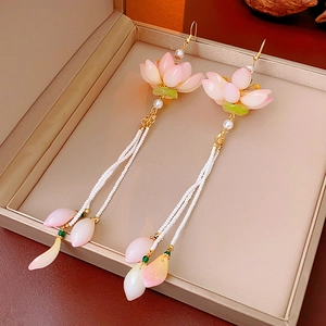 Macro shot of glass lotus pearl tassel earrings in a golden jewelry gift box