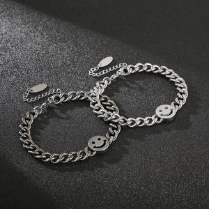 Macro view of silver stainless steel curb chain bracelet with circular smiley face charm