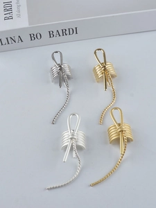 Macro shot of minimalist metal ear cuffs with sleek chain details in gold and silver
