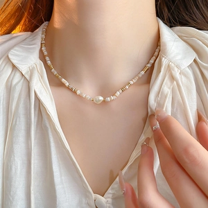Detail of baroque pearl necklace with shell beads and gold spacers on a neck model