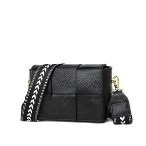 Detail of black woven leather crossbody bag featuring a wide geometric pattern strap