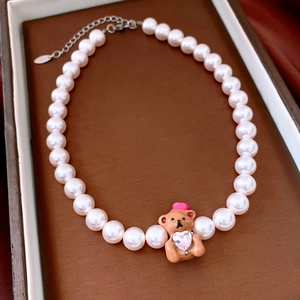 Detailed macro view of French style pearl necklace with cute bear and heart crystal pendant