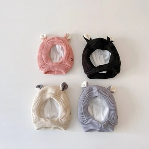 Flat lay of knit baby beanies in pink, black, beige and grey with animal ears and lining