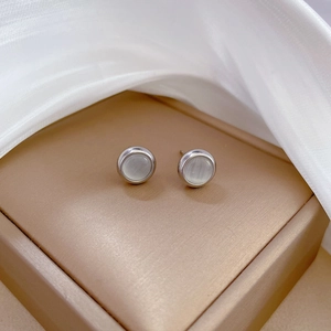 Detailed close-up of round cat-eye stone stud earrings on champagne gold jewelry box