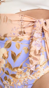 Detail of waist bow tie and floral print contrast on a stylish one-piece swimsuit