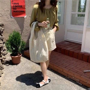 Floral canvas tote bag paired with yellow pleated top and beige shorts in a sunny outdoor setting