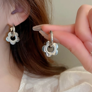 Detailed view of silver flower-shaped hoop earrings with a polished metallic finish
