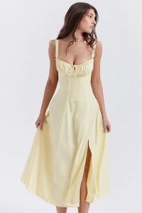 Detail of light yellow slip dress featuring a structured corset waist and pleated bust