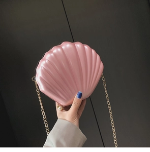 Detail view of pearlescent pink shell-shaped crossbody bag with a white pearl charm