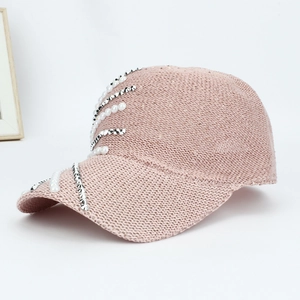 Detailed close-up of pink knit baseball cap with elegant pearls and sparkling rhinestones