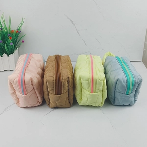 Detailed view of four quilted cosmetic bags in pink, brown, yellow, and blue nylon
