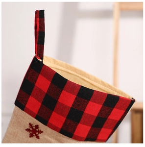 Detail of burlap Christmas stocking with red black plaid trim and snowflake embroidery
