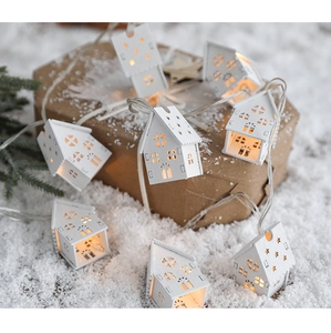 Detail of warm LED white wooden house fairy lights arranged on snow for Christmas decor
