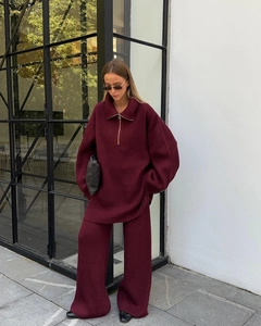 Detail of burgundy ribbed knit tracksuit featuring half-zip top and wide-leg trousers