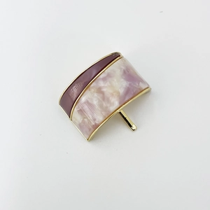 Detail of elegant two-tone pony hook with dark red and marble resin and gold metal edge