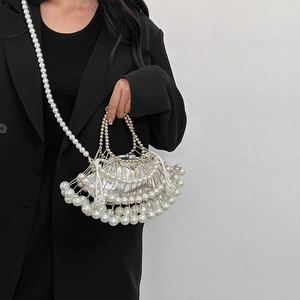 Elegant pearl handbag with metal frame and silver inner pouch worn by model