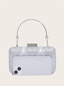 Silver evening bag with dense rhinestones shown next to a smartphone for size comparison