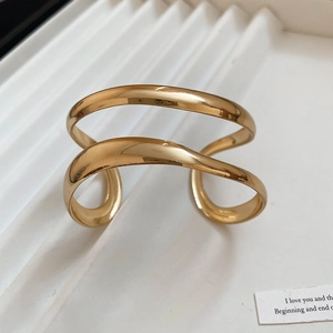 Close-up of golden geometric double-layer cuff bracelet with polished mirror finish